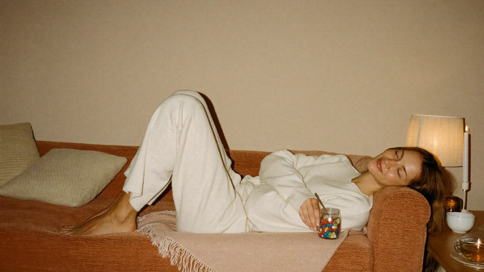 Relaxed mom unwinding on a cozy sofa in the evening with a small jar of gummies, illustrating what a 5mg THC gummy can feel like