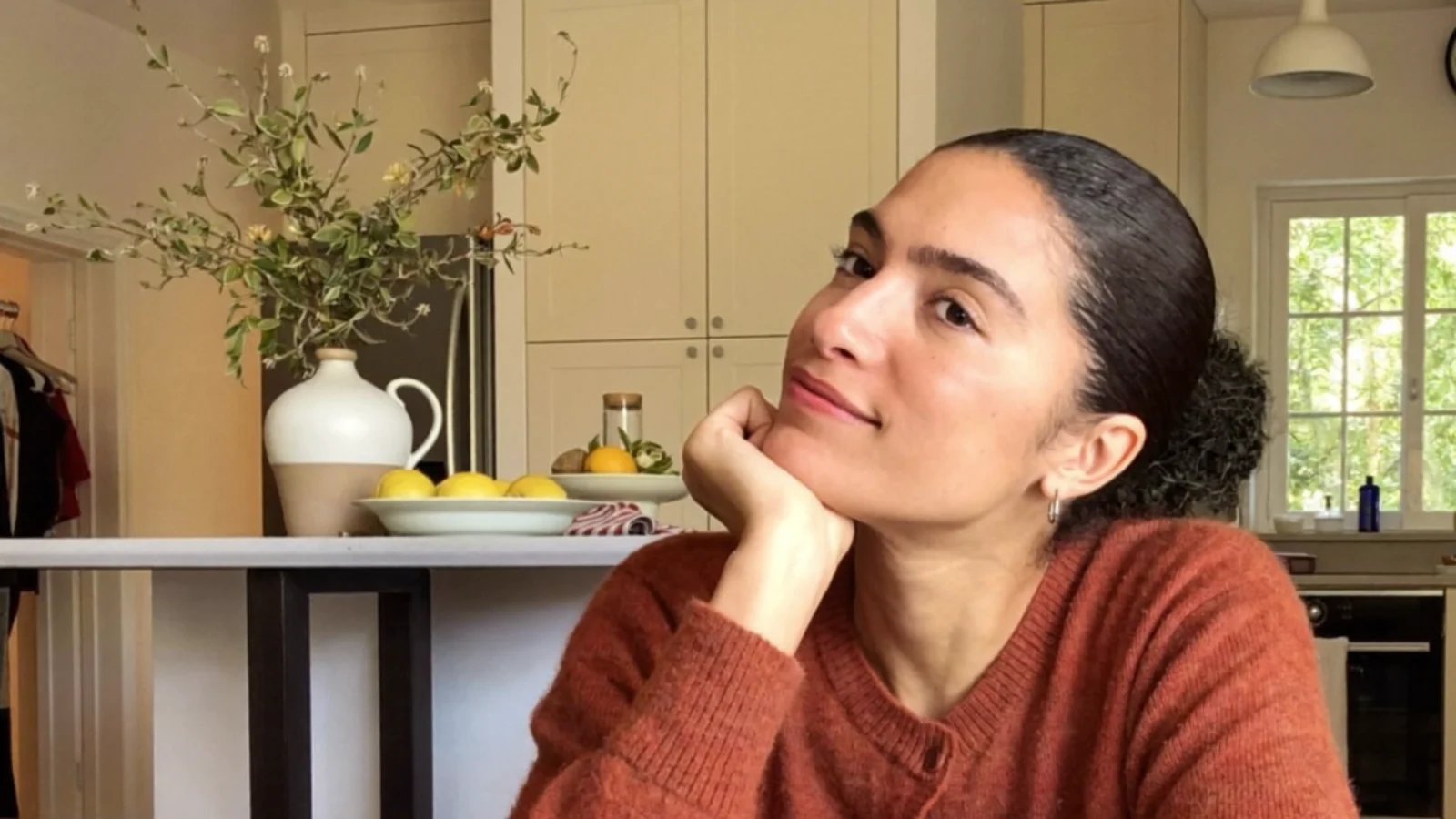 Thoughtful mom resting her chin on her hand at the kitchen table with coffee, wondering whether weed is a depressant or a stimulant