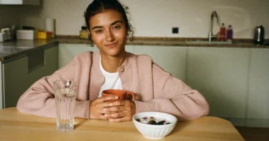 Sleepy mom at the kitchen table in the morning with a mug, a glass of water and a bowl of yogurt, easing through a THC hangover