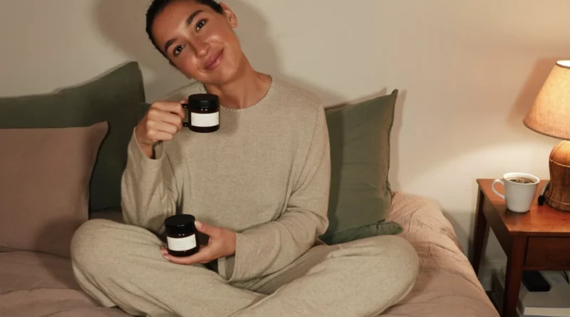 Relaxed mom in cozy loungewear on her bed in the evening holding a jar of CBN gummies, with herbal tea on the nightstand